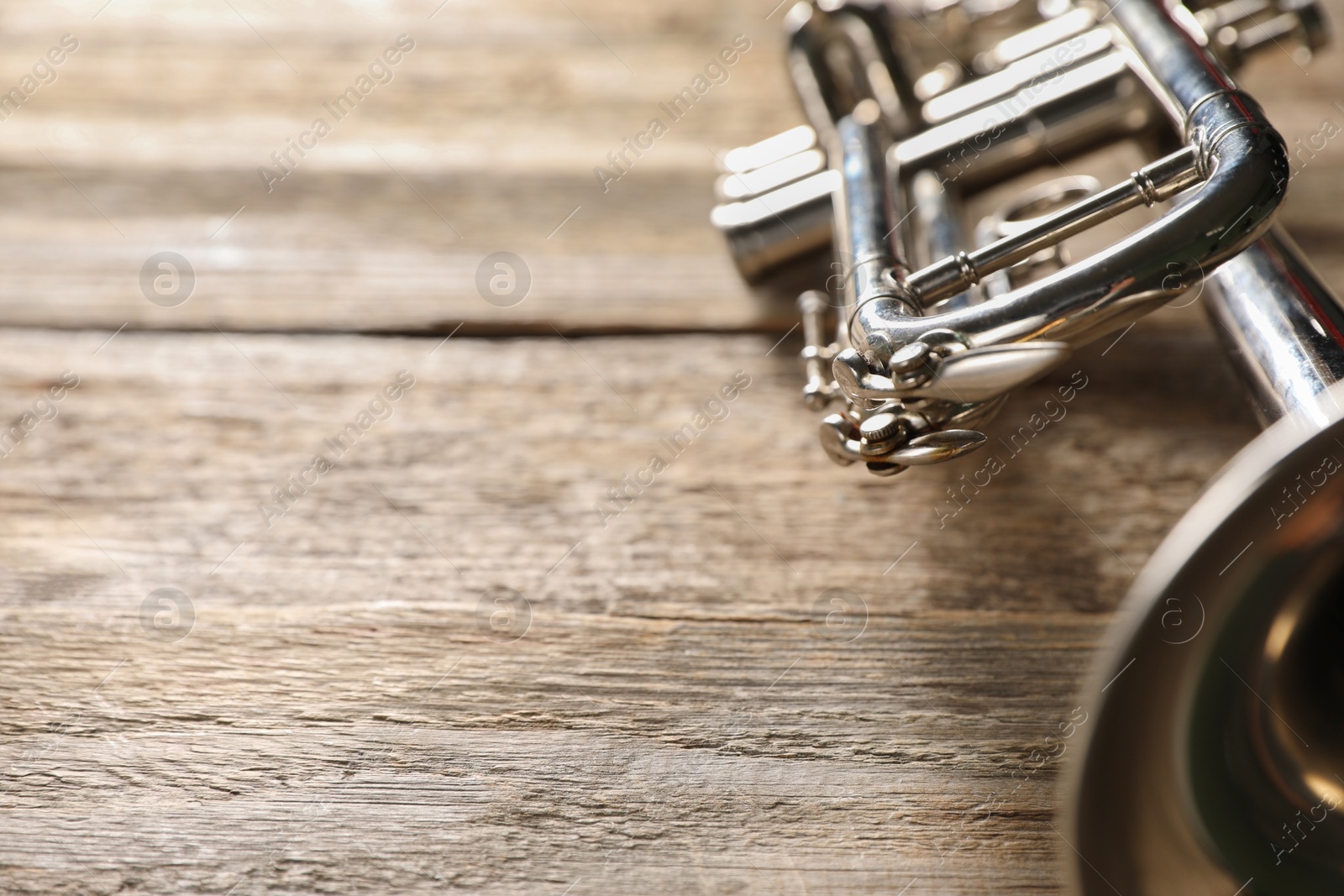 Photo of One trumpet on wooden table, closeup. Space for text