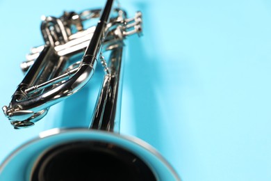 Photo of One trumpet on light blue background, closeup. Space for text