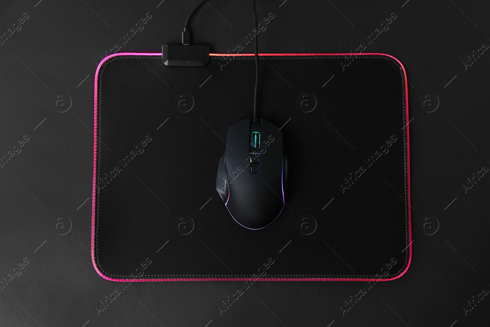 Photo of Computer mouse and mousepad on black background, top view