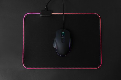 Photo of Computer mouse and mousepad on black background, top view