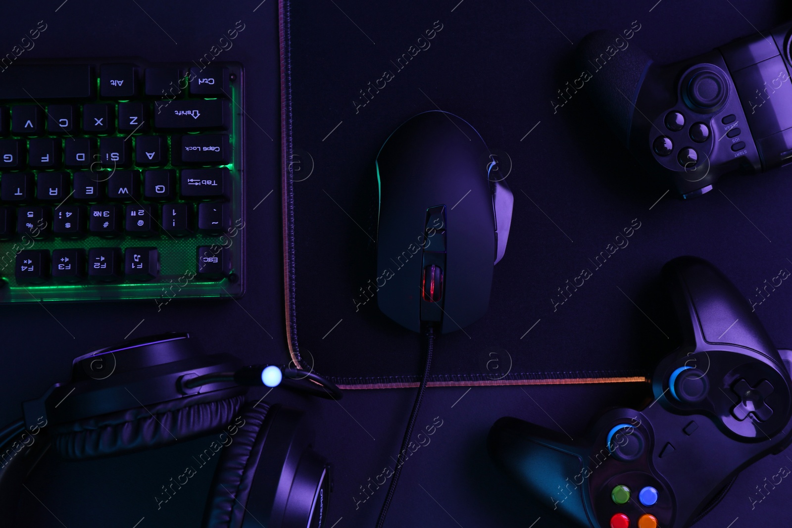 Photo of Computer mouse, RGB keyboard, game controllers and headset on black background, top view