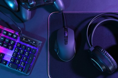 Photo of Computer mouse, RGB keyboard, game controllers and headset on black background, top view