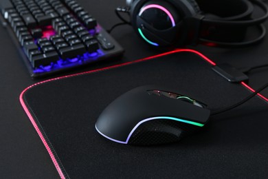 Computer mouse, mousepad, RGB keyboard and headset on black background