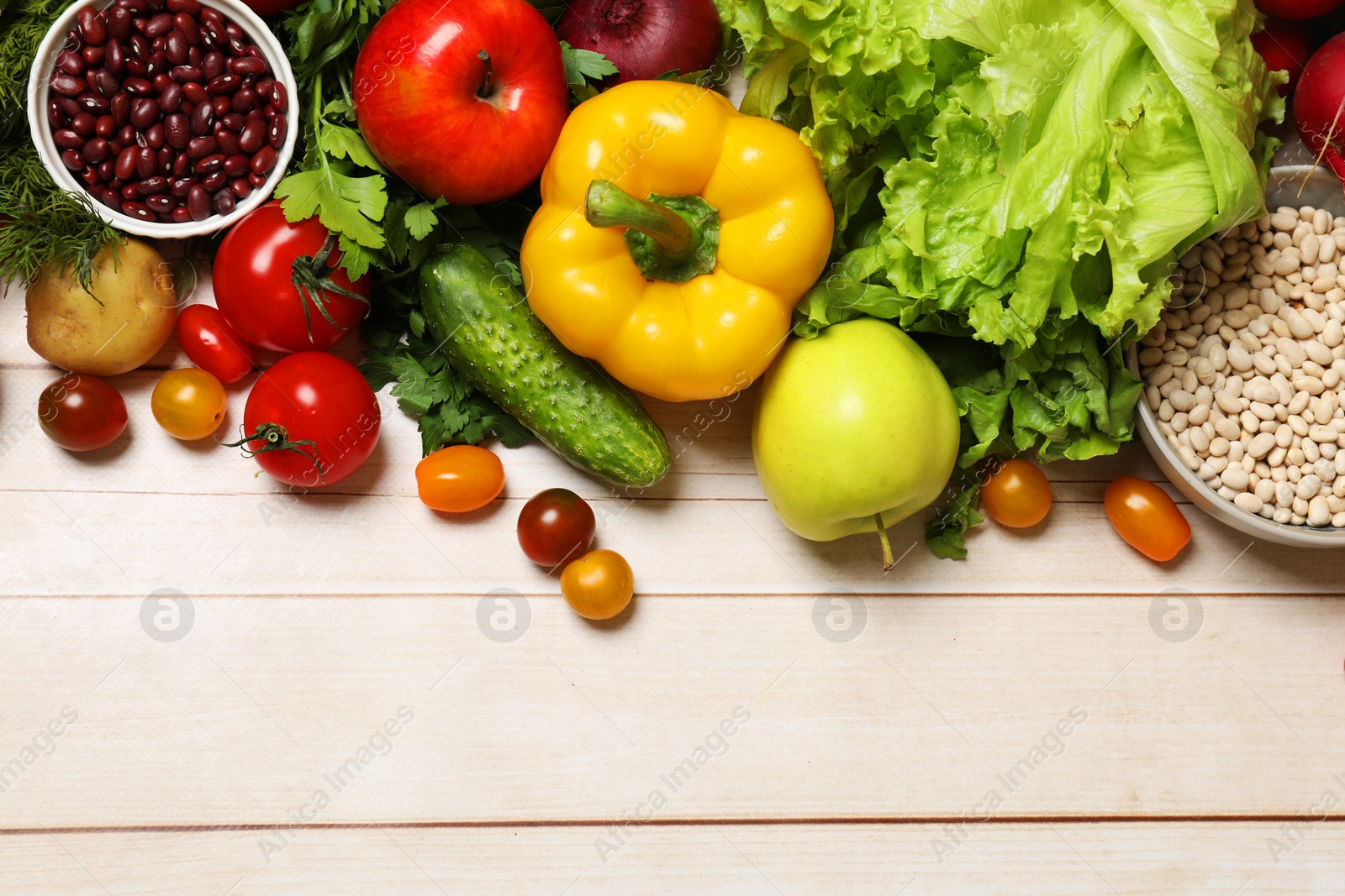 Photo of Different vegetarian products on light wooden table, top view. Space for text