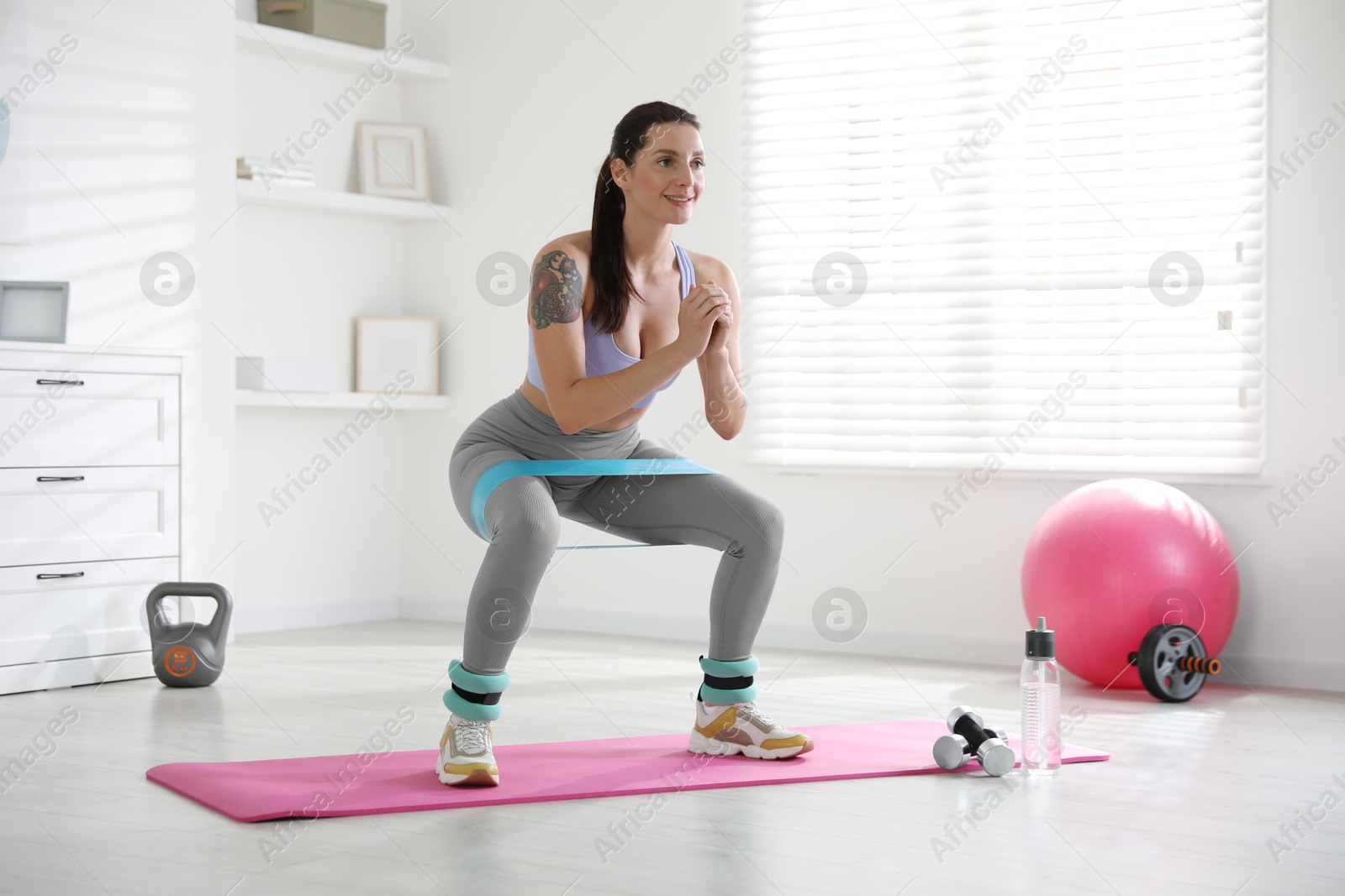 Photo of Woman with ankle weights and elastic band training indoors