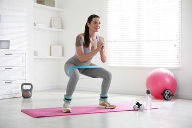 Woman with ankle weights and elastic band training indoors