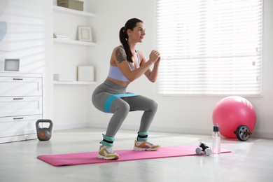 Photo of Woman with ankle weights and elastic band training indoors