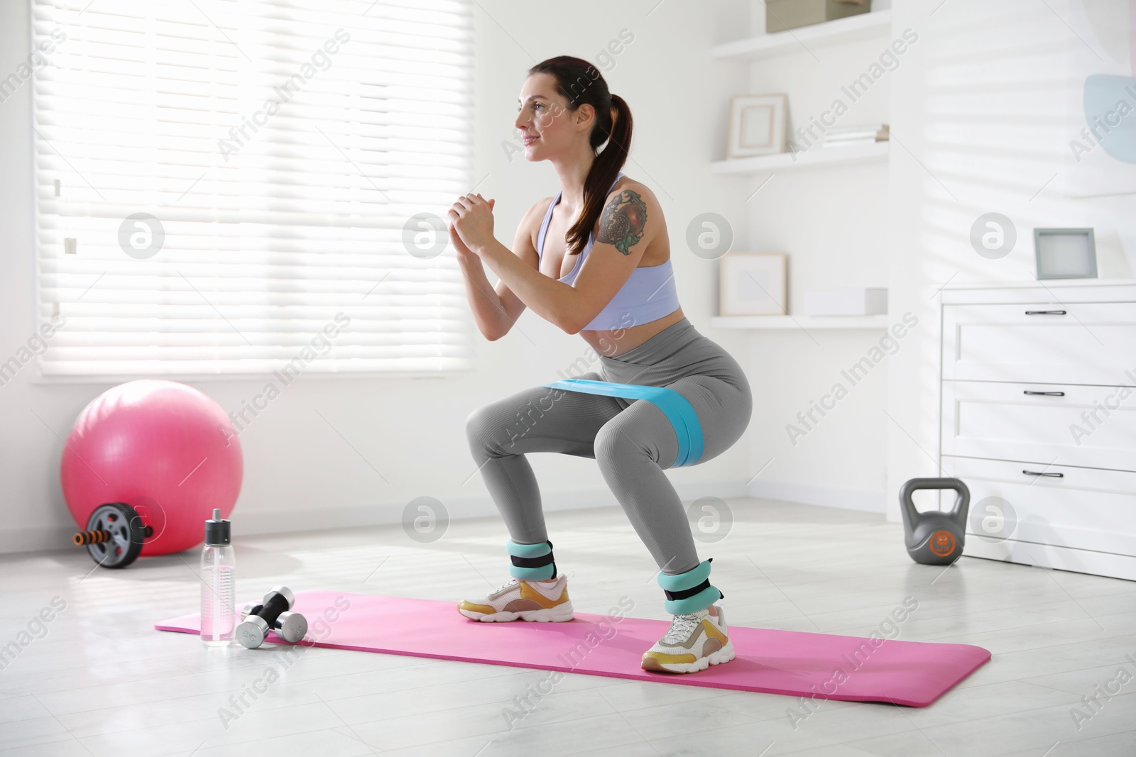 Photo of Woman with ankle weights and elastic band training indoors