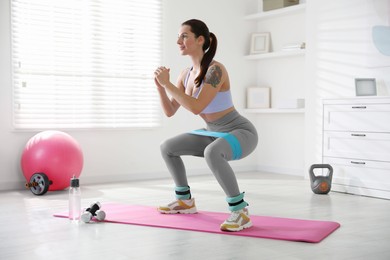 Woman with ankle weights and elastic band training indoors