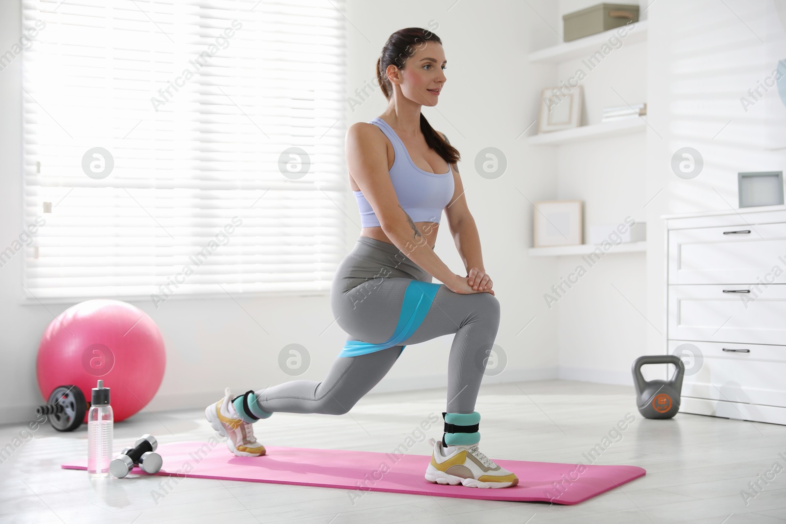 Photo of Woman with ankle weights and elastic band training indoors