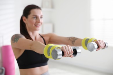 Beautiful woman with ankle weights and dumbbells training indoors