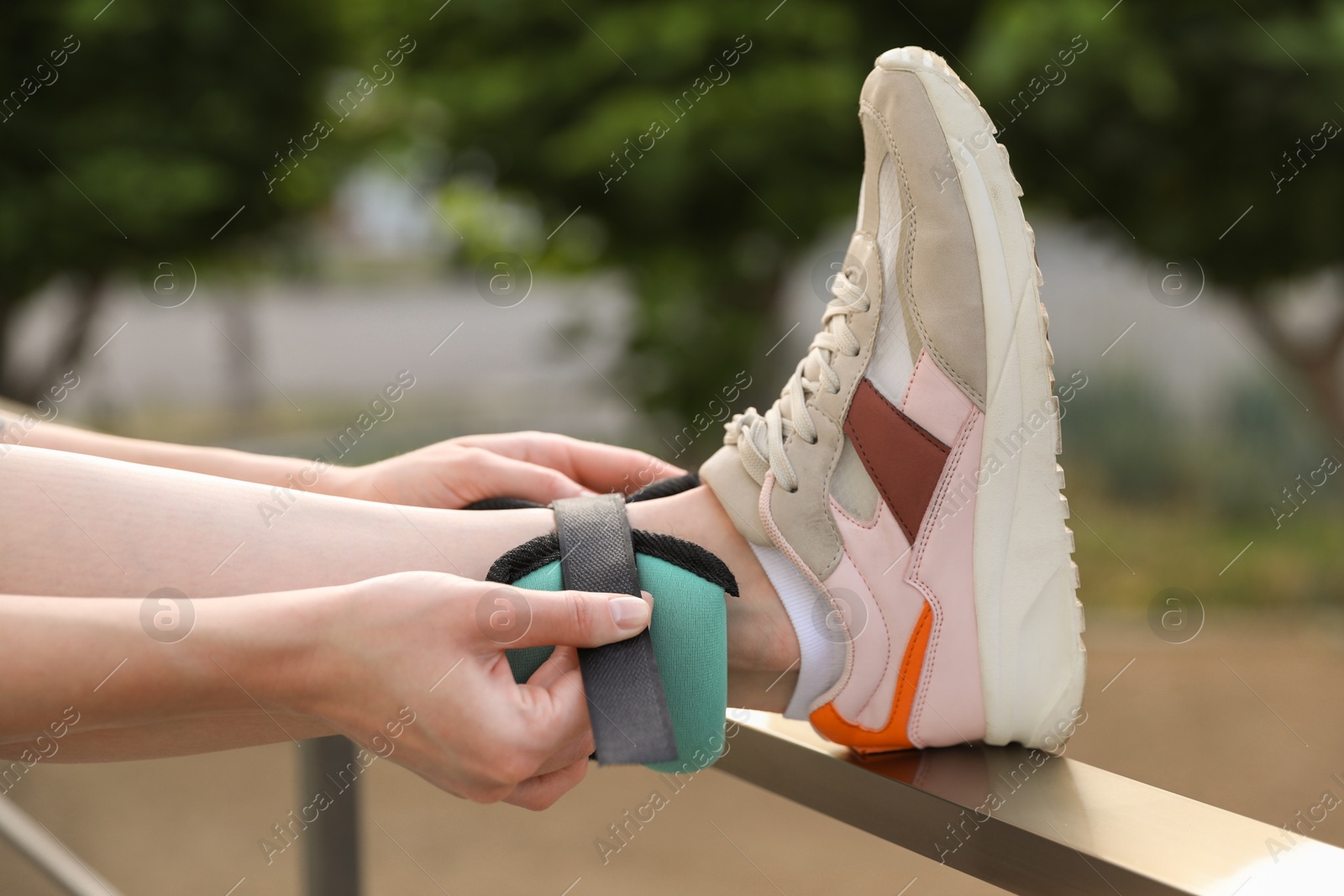 Photo of Woman putting on ankle weight outdoors, closeup