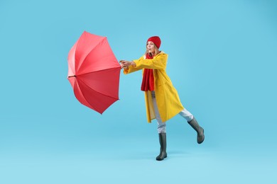 Woman with red umbrella on light blue background