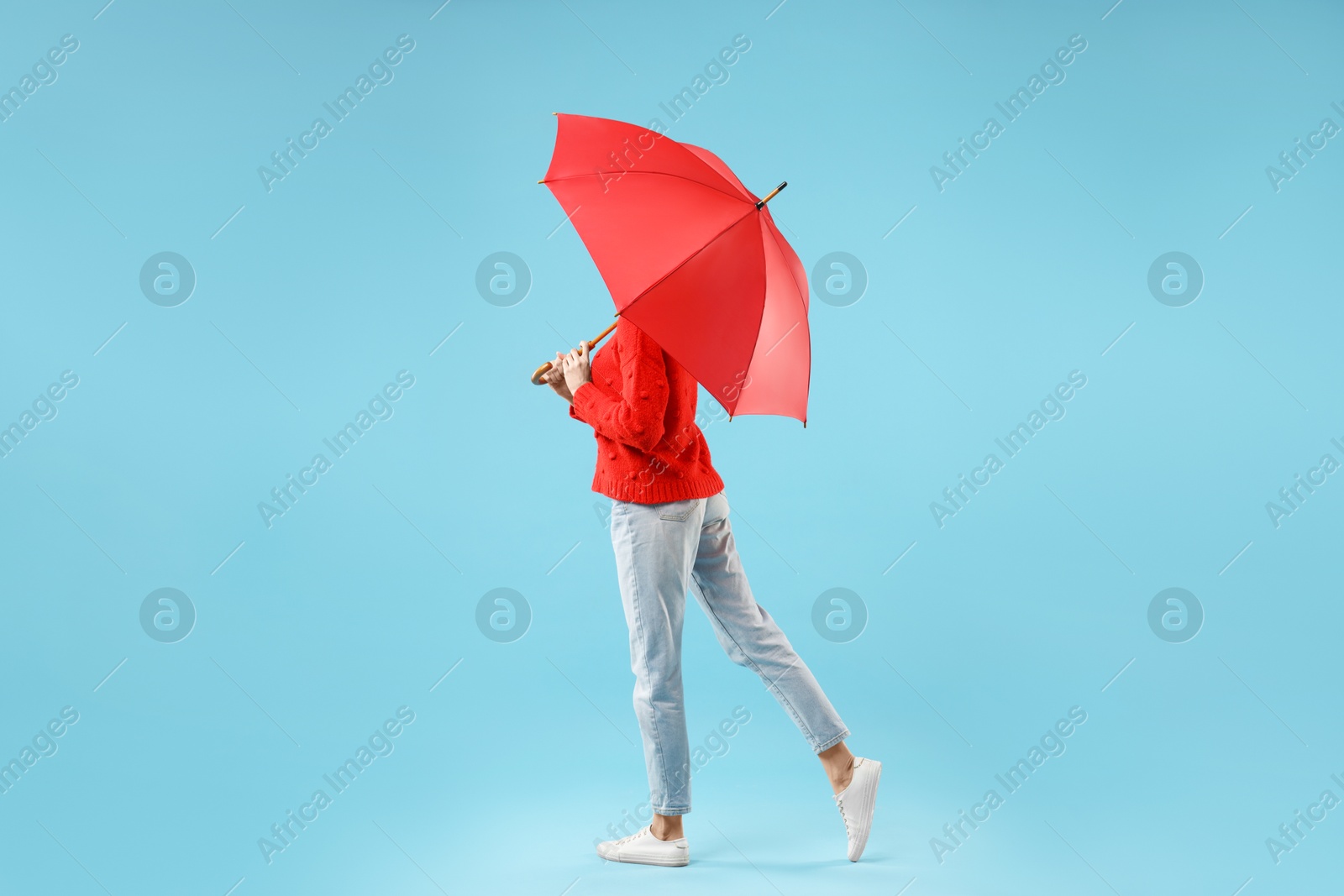 Photo of Woman with red umbrella on light blue background