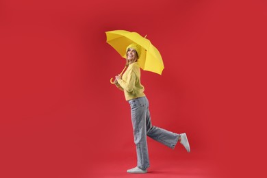 Photo of Woman with yellow umbrella on red background