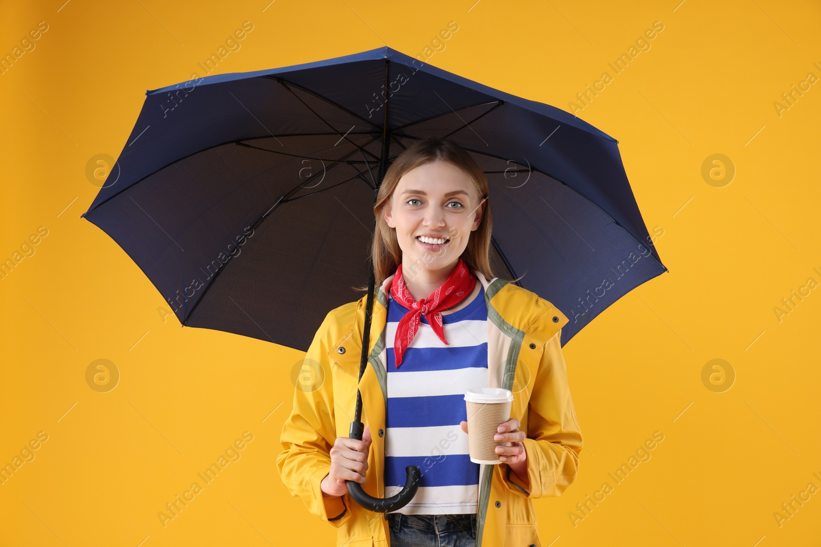 Photo of Woman with blue umbrella and paper cup on yellow background