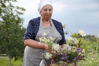 Photo of Senior woman with wildflowers for tincture outdoors