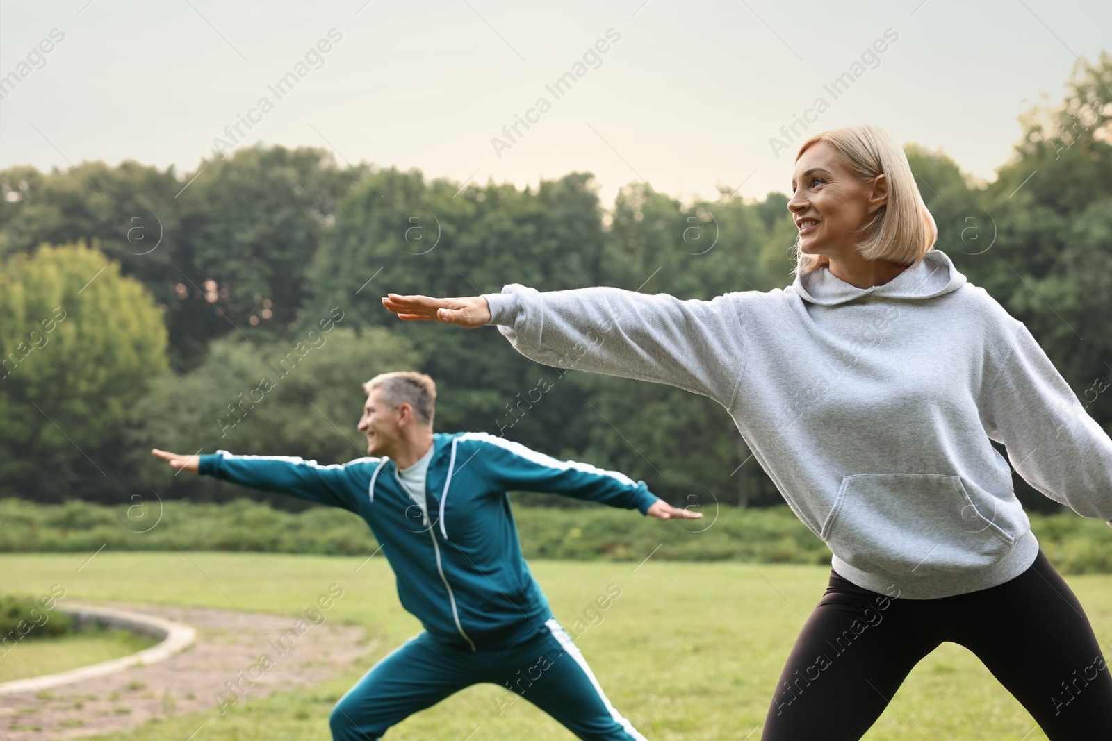 Photo of Happy couple doing exercises in park, selective focus