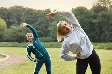 Happy couple doing exercises in park, selective focus