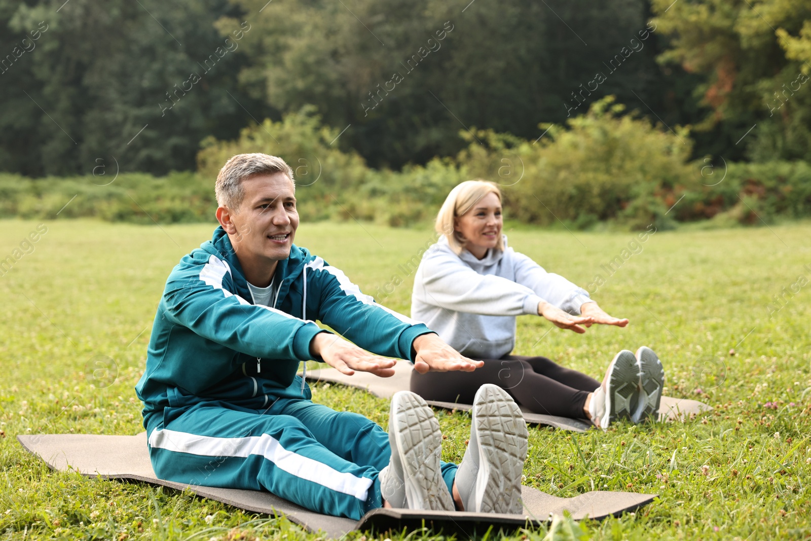 Photo of Happy couple doing exercises in park, selective focus