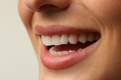 Photo of Smiling woman with healthy clean teeth on light background, closeup