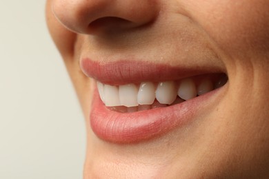 Photo of Smiling woman with healthy clean teeth on light background, closeup