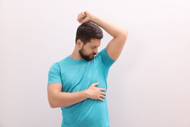 Photo of Emotional man in t-shirt before using deodorant on white background