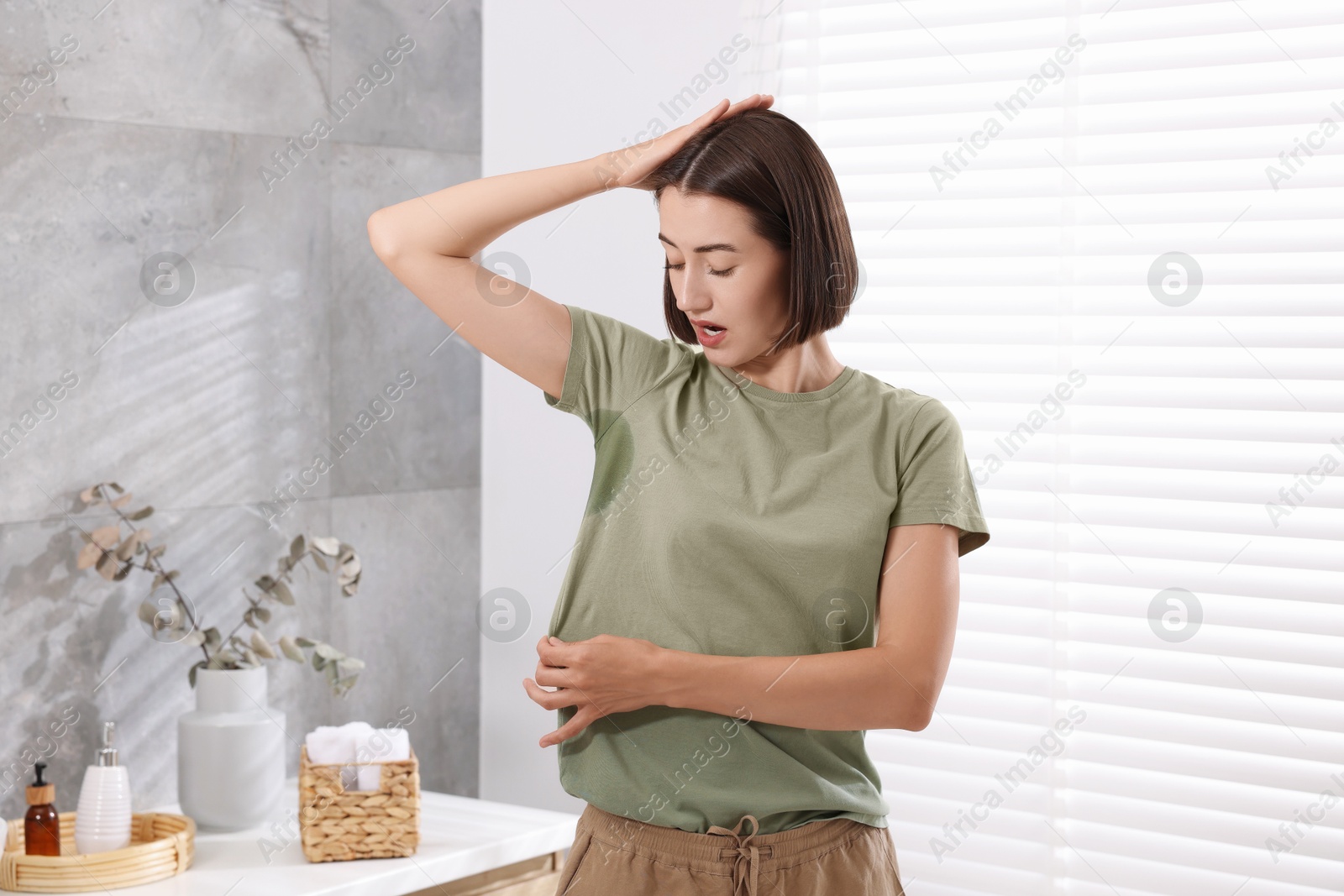 Photo of Emotional woman in t-shirt before using deodorant at home