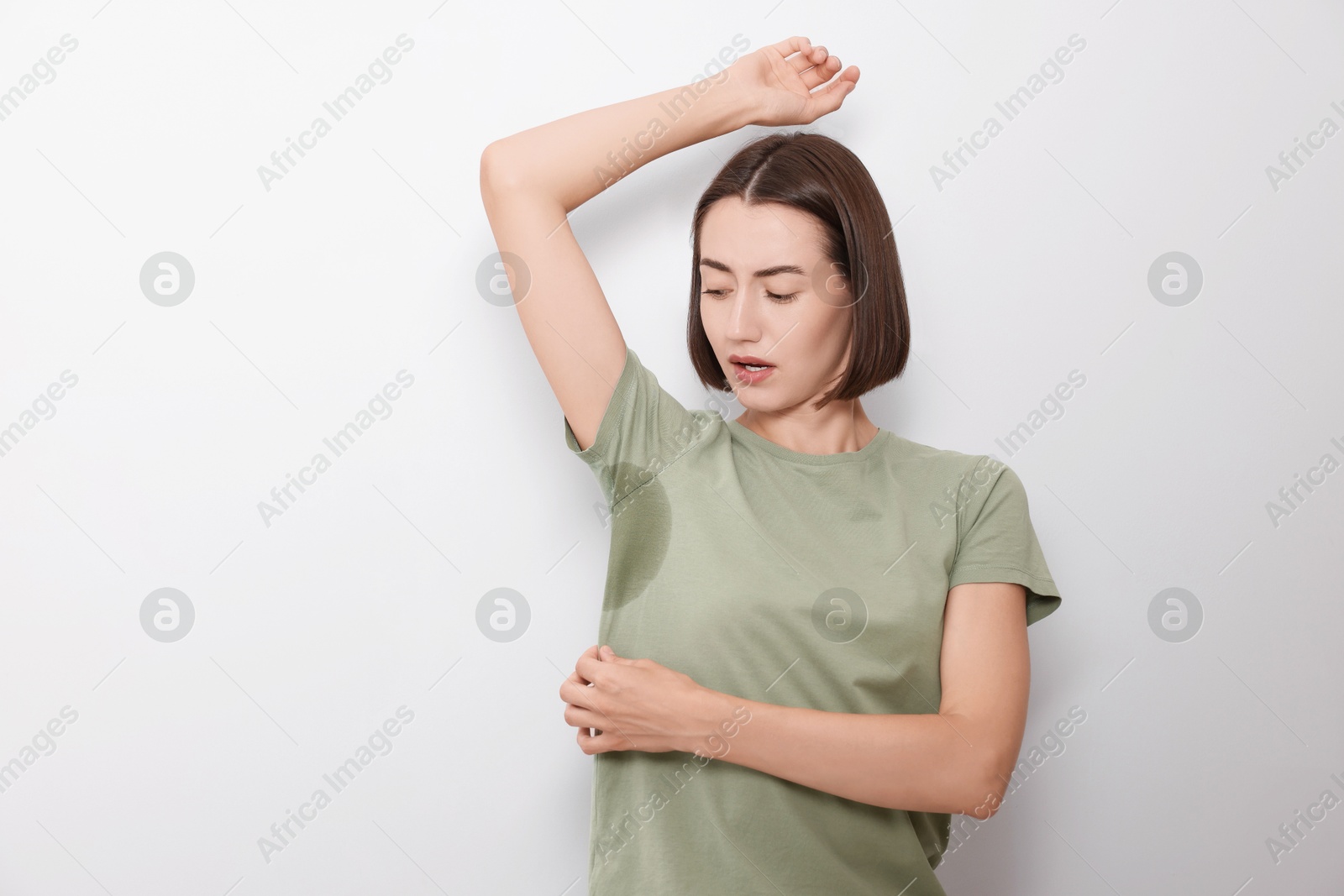 Photo of Emotional woman in t-shirt before using deodorant on white background