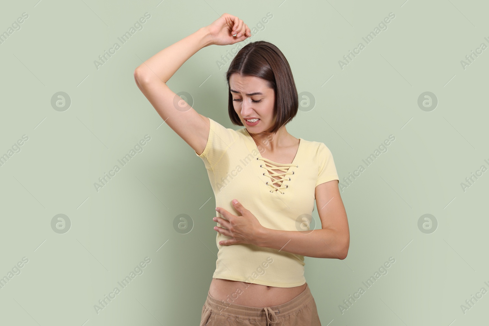 Photo of Emotional woman in t-shirt before using deodorant on green background