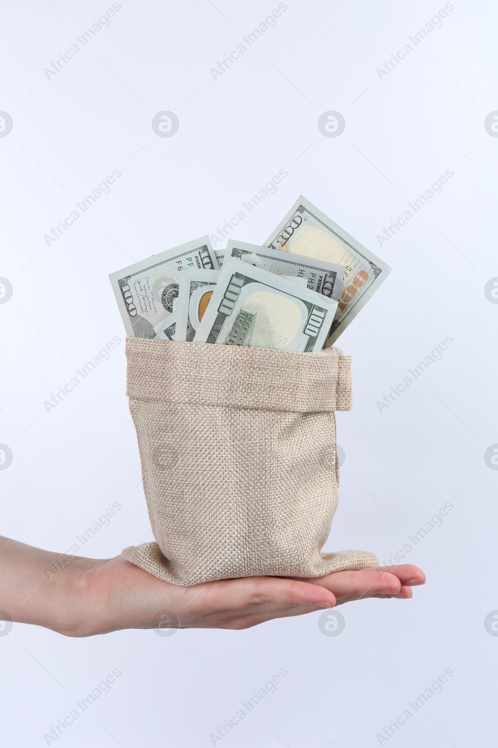 Photo of Woman with bag of dollar banknotes against light background, closeup