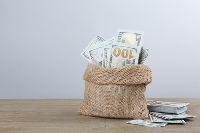 Photo of Dollar banknotes in bag on wooden table, space for text