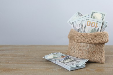 Photo of Dollar banknotes in bag on wooden table, space for text