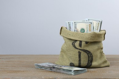 Photo of Dollar banknotes in bag on wooden table, space for text