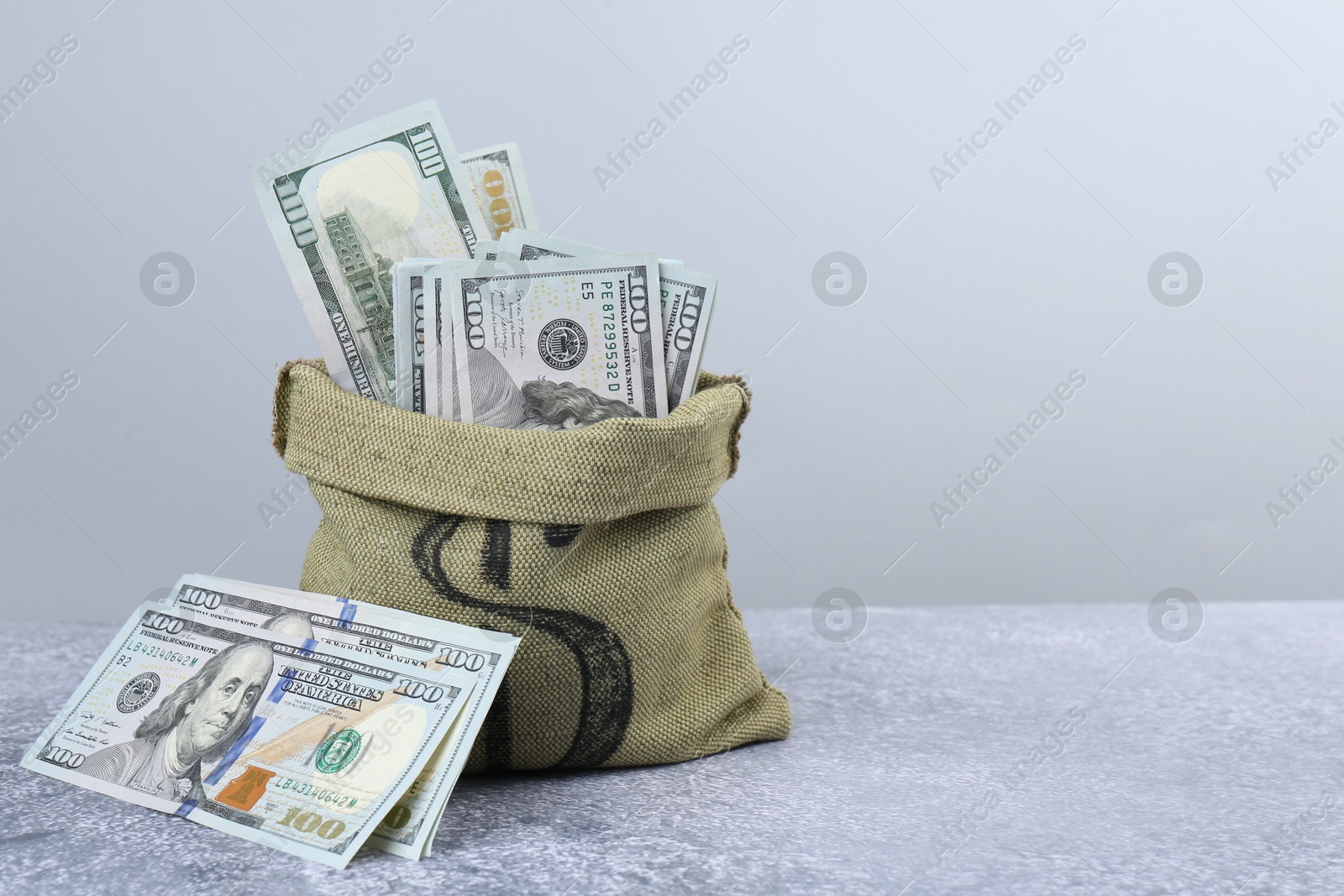 Photo of Dollar banknotes in bag on grey textured table, space for text