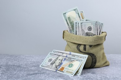 Photo of Dollar banknotes in bag on grey textured table, space for text