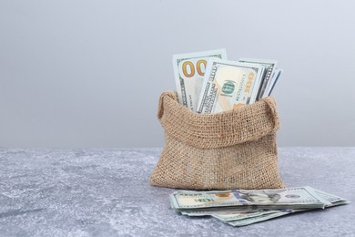 Photo of Dollar banknotes in bag on grey textured table, space for text