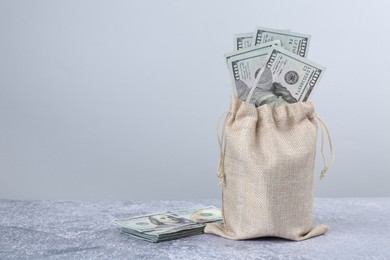 Photo of Dollar banknotes in bag on grey textured table, space for text