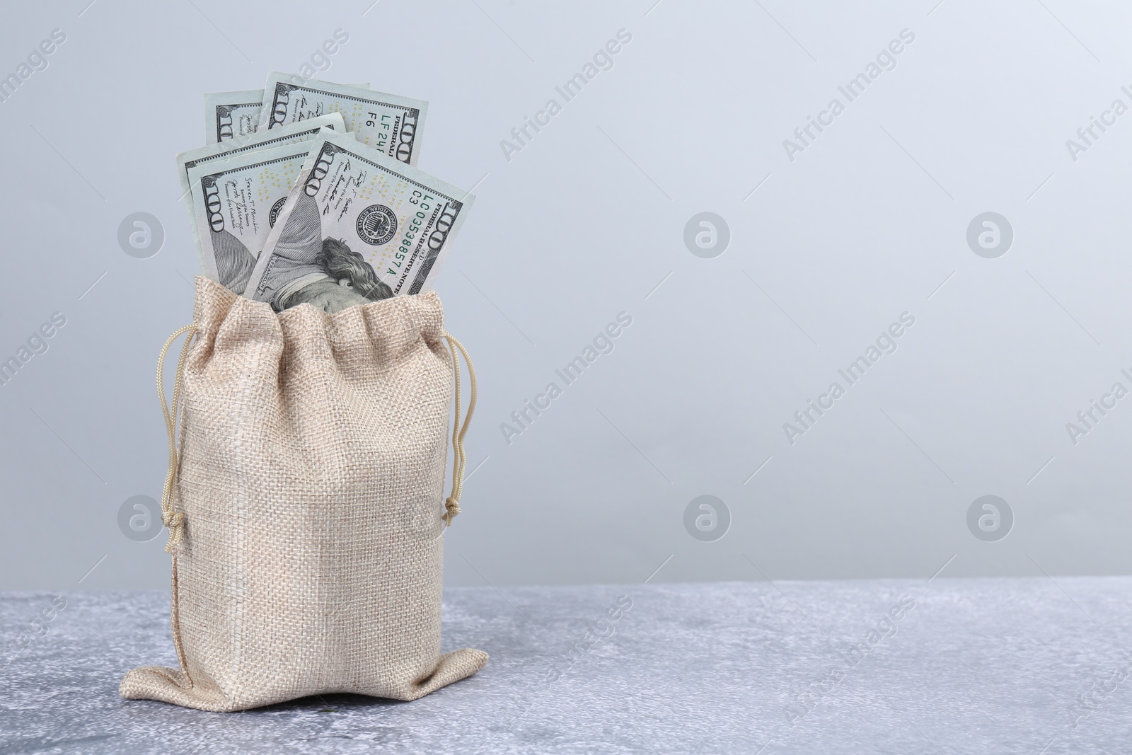 Photo of Dollar banknotes in bag on grey textured table, space for text