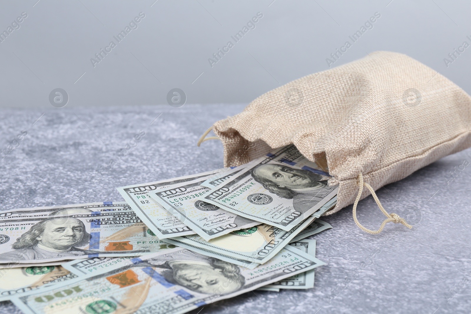 Photo of Dollar banknotes in bag on grey textured table, closeup