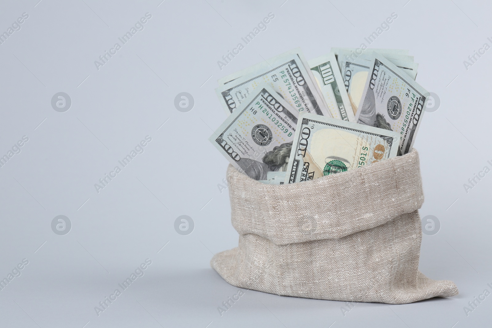 Photo of Dollar banknotes in bag on grey background, space for text