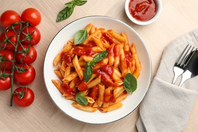 Photo of Delicious pasta with tomato sauce and basil in bowl served on wooden table, flat lay