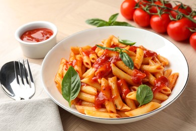 Photo of Delicious pasta with tomato sauce and basil in bowl served on wooden table, closeup