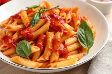 Photo of Delicious pasta with tomato sauce and basil in bowl on table, closeup