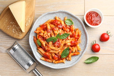 Photo of Delicious pasta with tomato sauce, basil and cheese on wooden table, flat lay