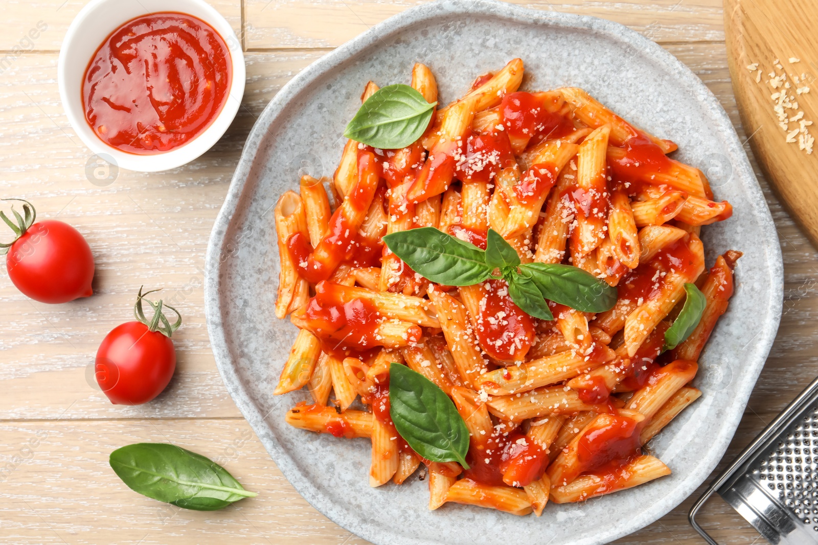 Photo of Delicious pasta with tomato sauce, basil and cheese on wooden table, flat lay