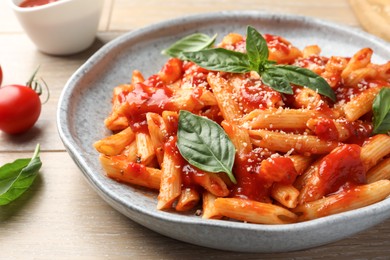 Delicious pasta with tomato sauce, basil and cheese on wooden table, closeup