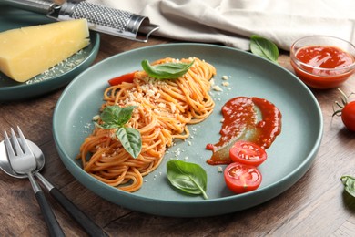 Photo of Delicious pasta with tomato sauce, basil and cheese served on wooden table, closeup