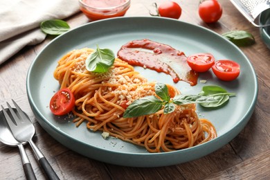 Photo of Delicious pasta with tomato sauce, basil and cheese served on wooden table, closeup