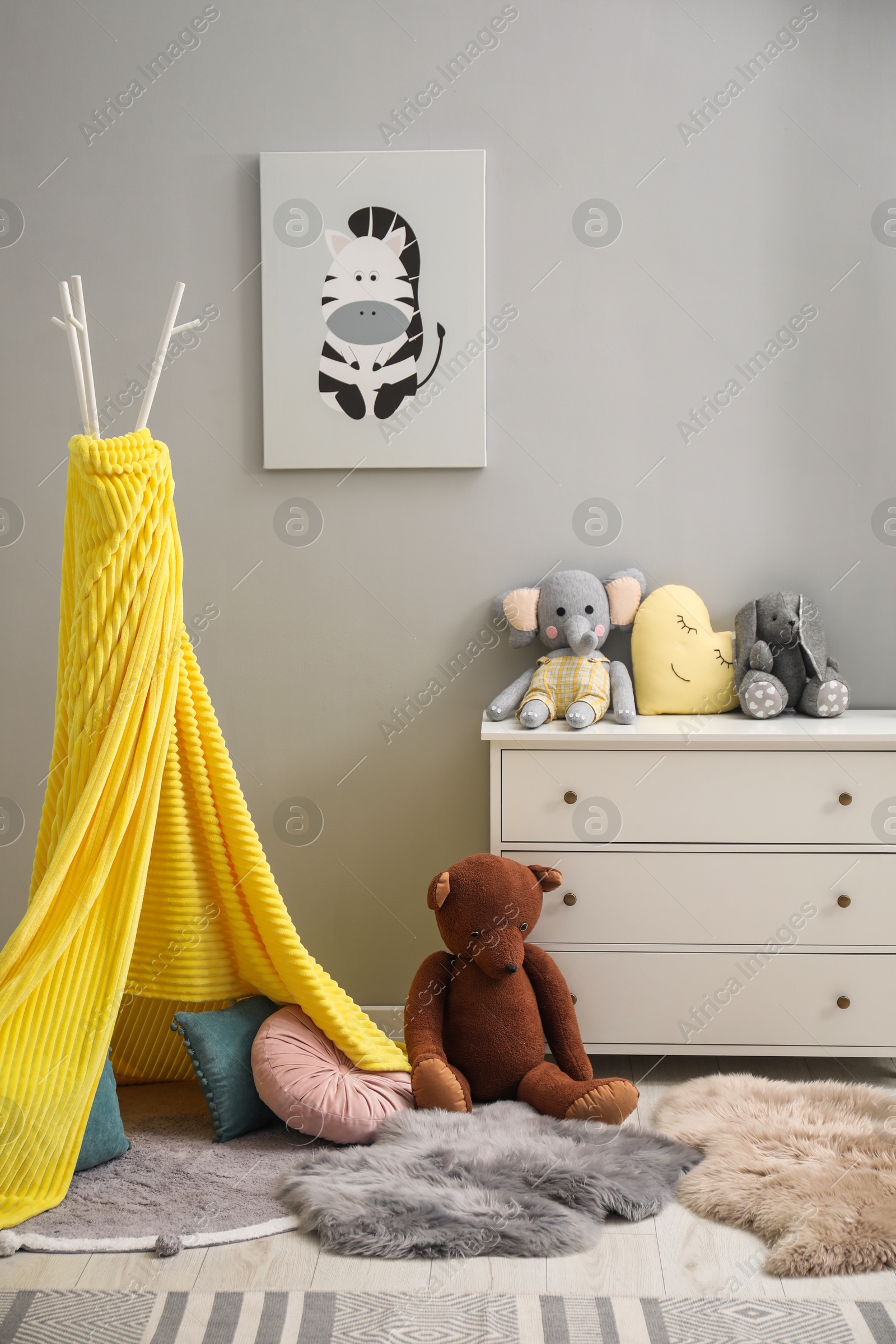 Photo of Play tent, toys, chest of drawers and picture in child room. Interior design